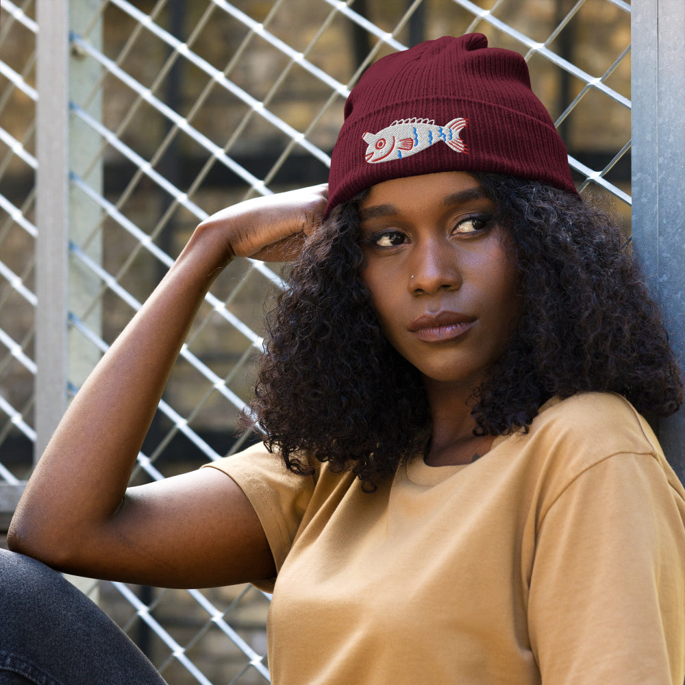 A woman wearing a burgundy Fishful Thinking organic ribbed beanie with embroidered unicornfish