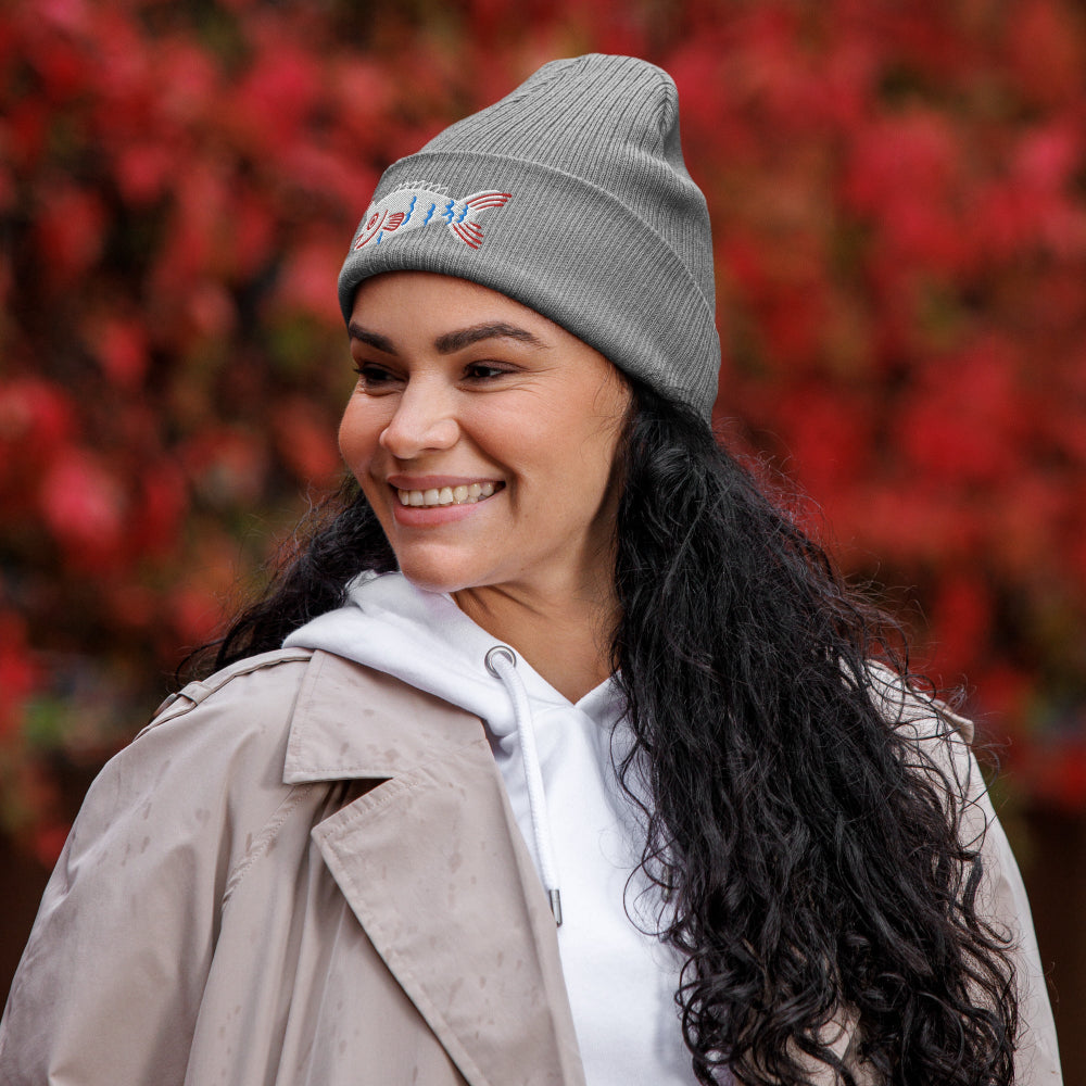 A woman wearing a grey Fishful Thinking organic ribbed beanie with embroidered unicornfish
