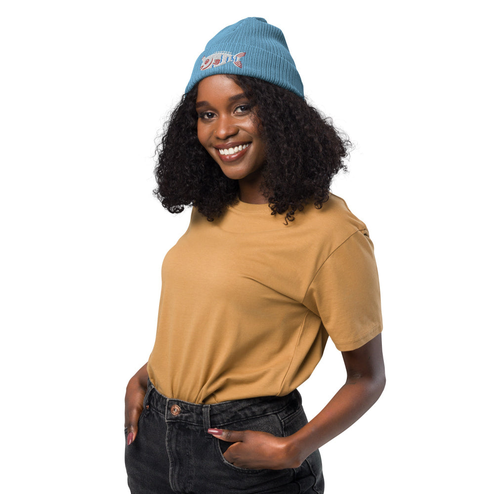 A woman wearing a light blue Fishful Thinking organic ribbed beanie with embroidered unicornfish