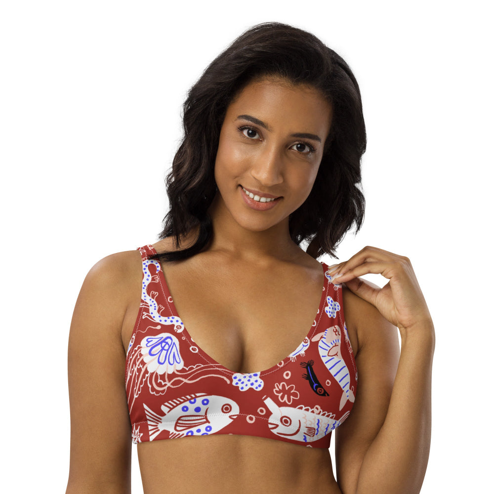 A woman is wearing a red bikini top with a funny fish pattern. The top features a V-neck design and a tie-up back.