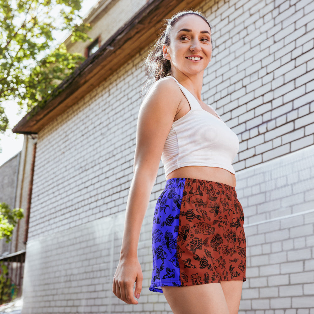 Front view of a woman wearing the Harlequin recycled unisex shorts outdoors