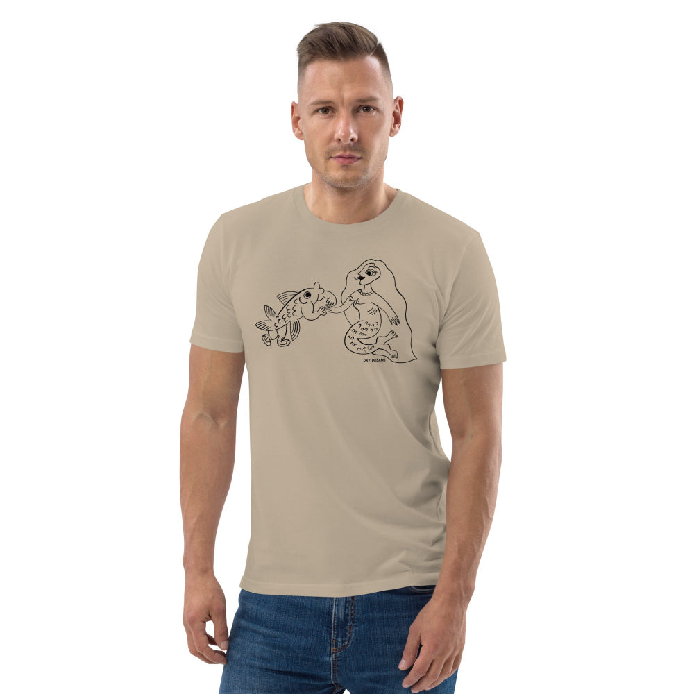 A male model wearing a beige unisex organic cotton t-shirt with a graphic print of a mermaid and a fish.