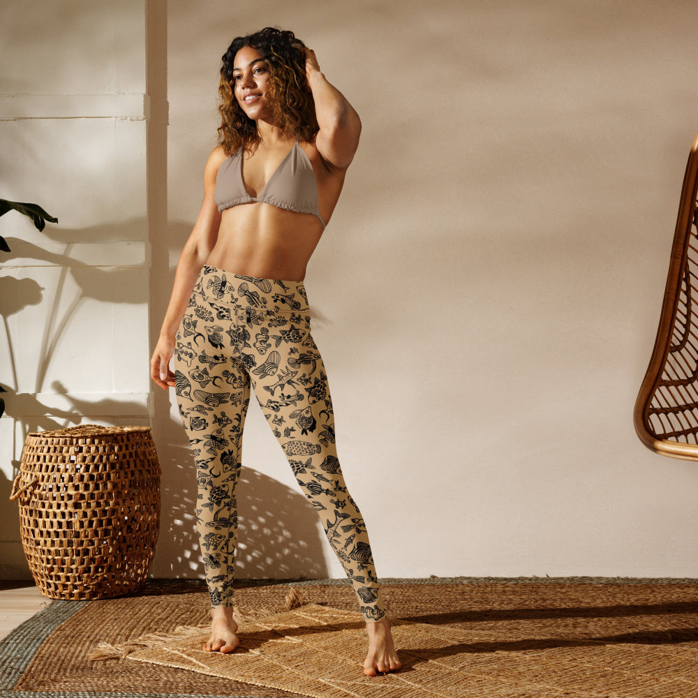A cheerful woman wearing Plenty of Fish in The Sea recycled leggings in a studio setting, front view