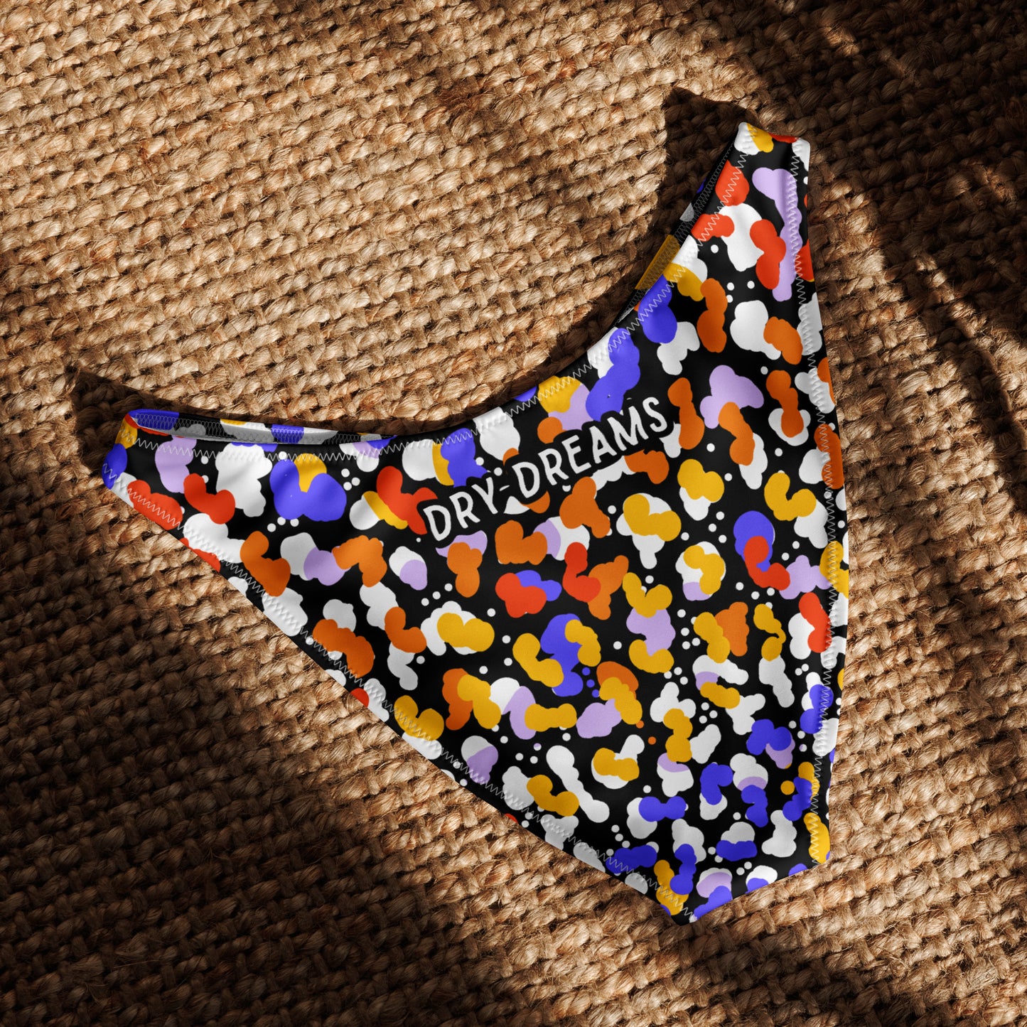 Flat lay of the Reef Roar recycled V-cut bikini bottom back on a textured background in sunlight