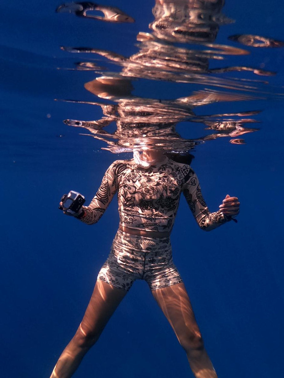 Woman floating in water with a Dry Dreams yoga set on, fins on her legs