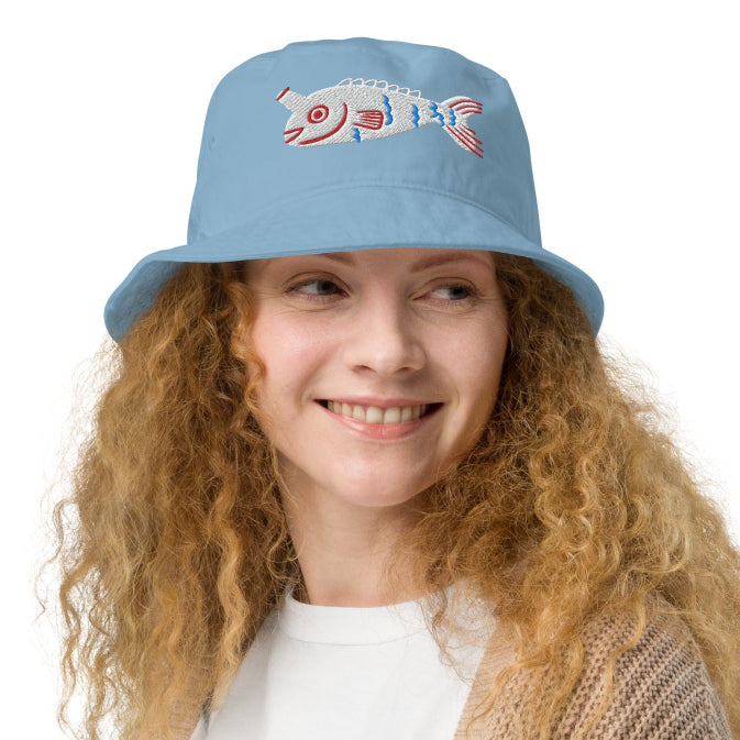 A woman wearing a light blue Fishful Thinking organic bucket hat with embroidered fish design