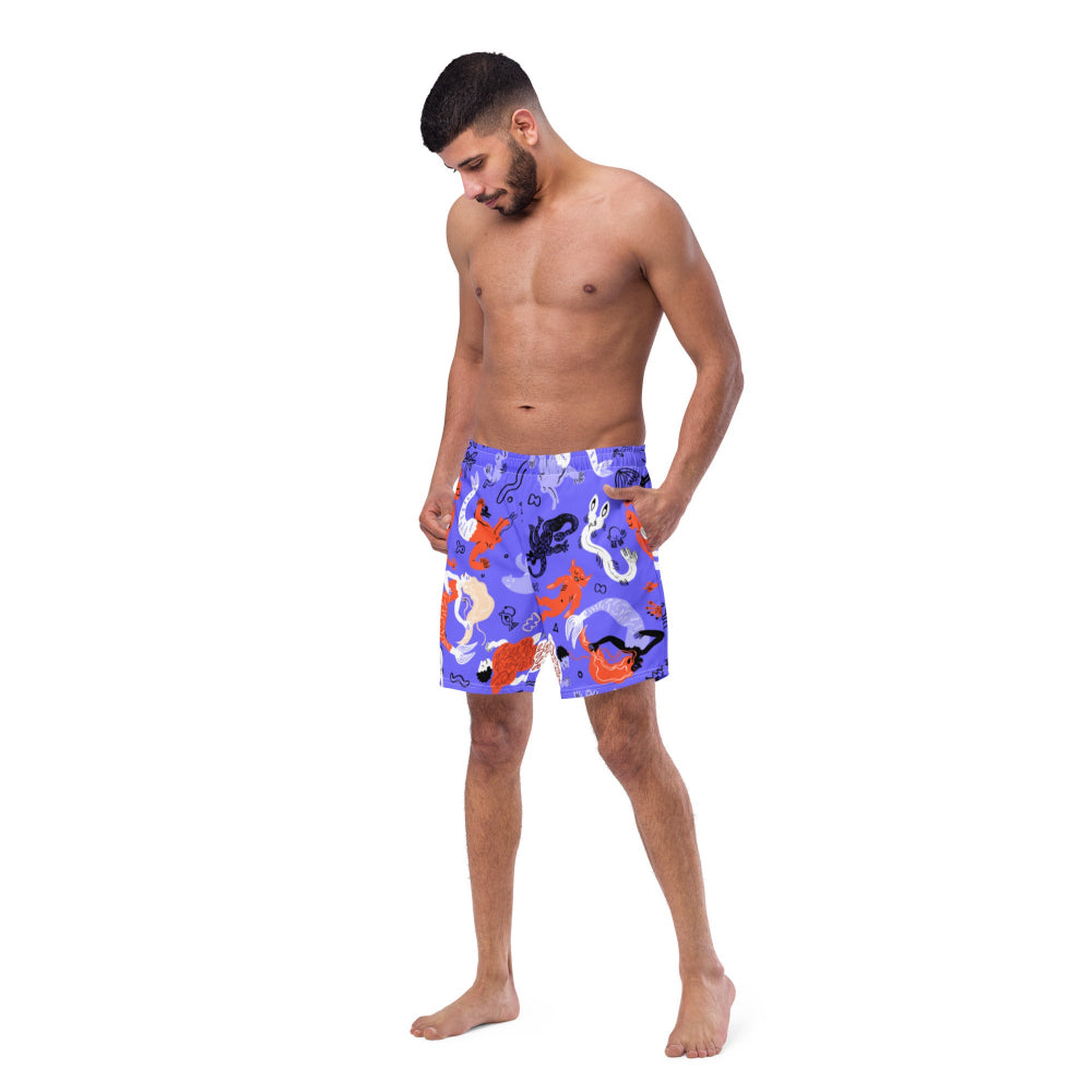 Left front view of a person wearing vibrant blue Funky Merfolk recycled swimming trunks with merfolk illustrations